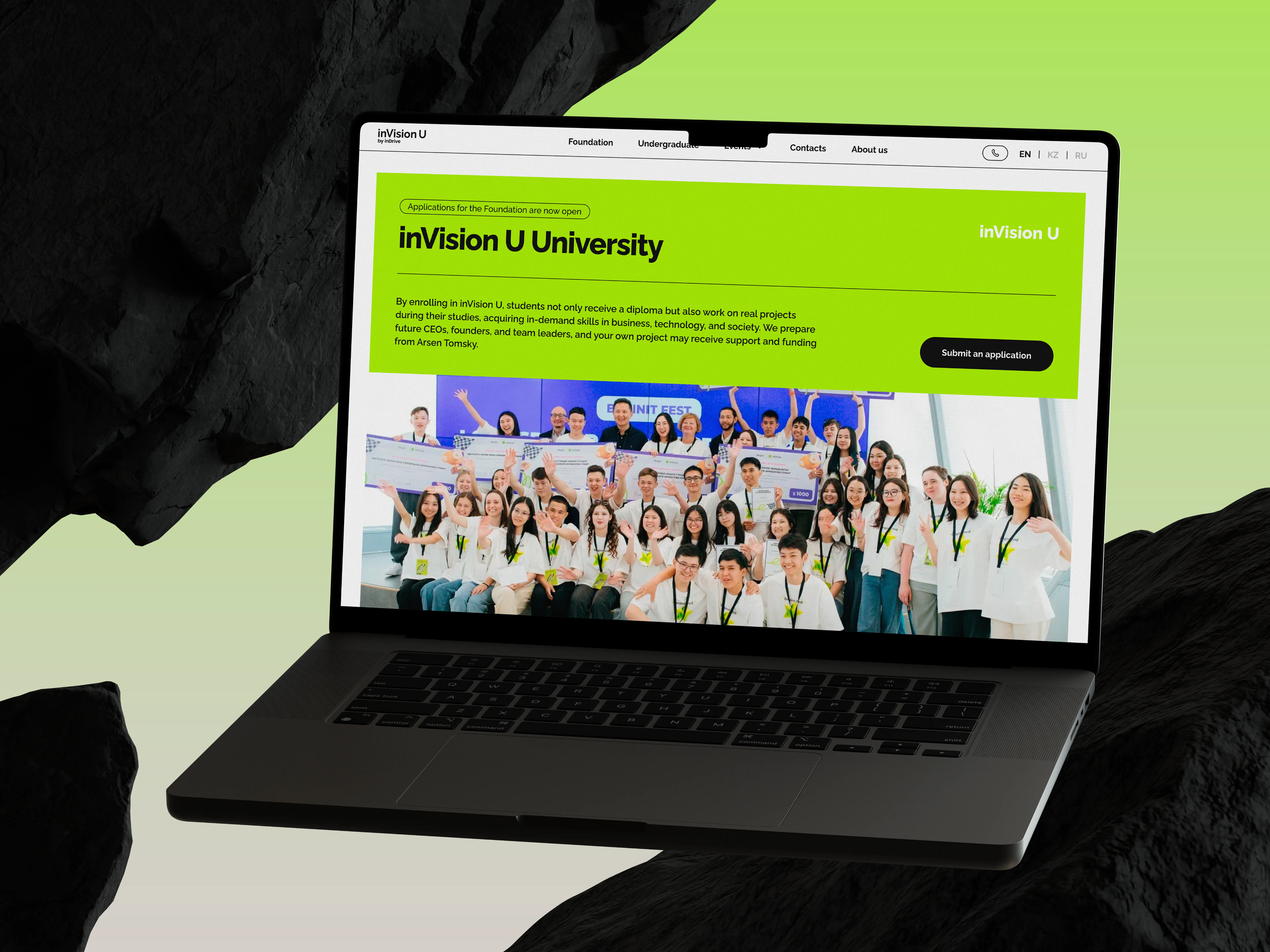 A laptop displays the inVision U University webpage featuring a large group photo of smiling students in white shirts with green lanyards, set against a lime green background.