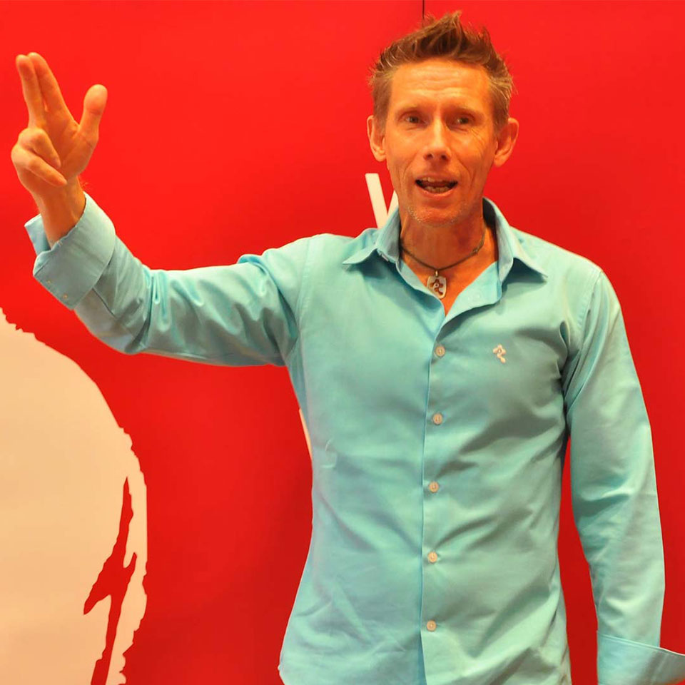 Dr. Detlef Reis speaking in front of a red backdrop