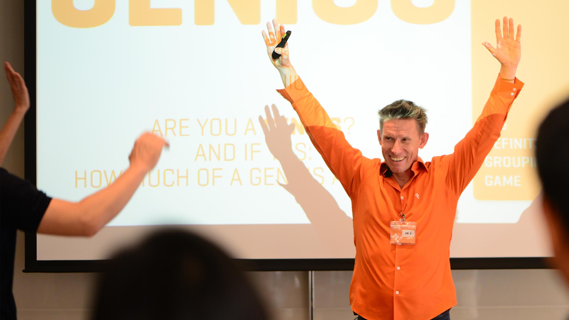 Dr. Detlef Reis presenting on stage with arms raised