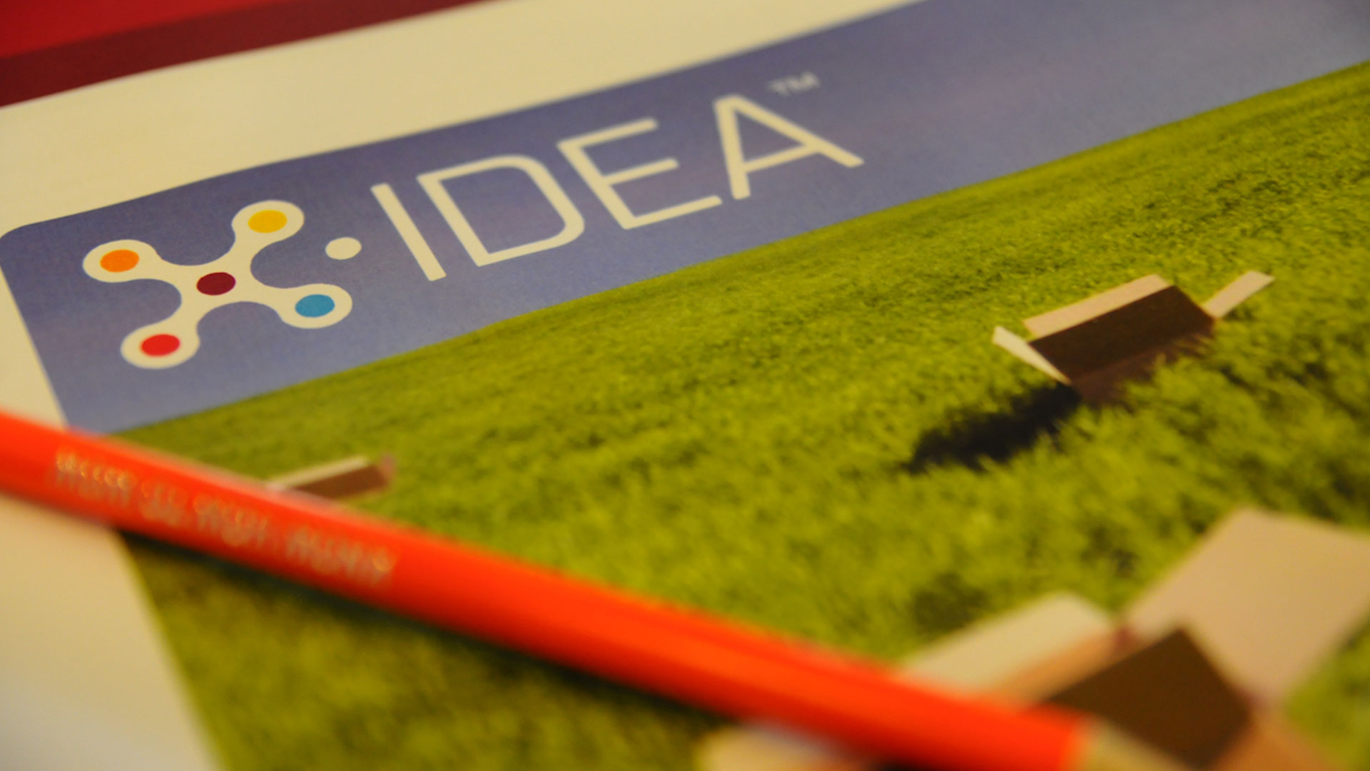 X-IDEA branded notebook and pen on grass