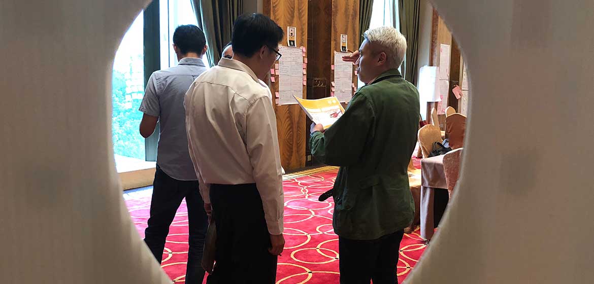 Covestro Shanghai participants talking in small groups, seen through a decorative screen
