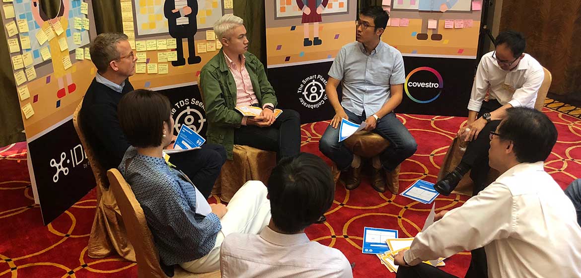 Small group discussion beside X-IDEA and Covestro banners at the Shanghai workshop