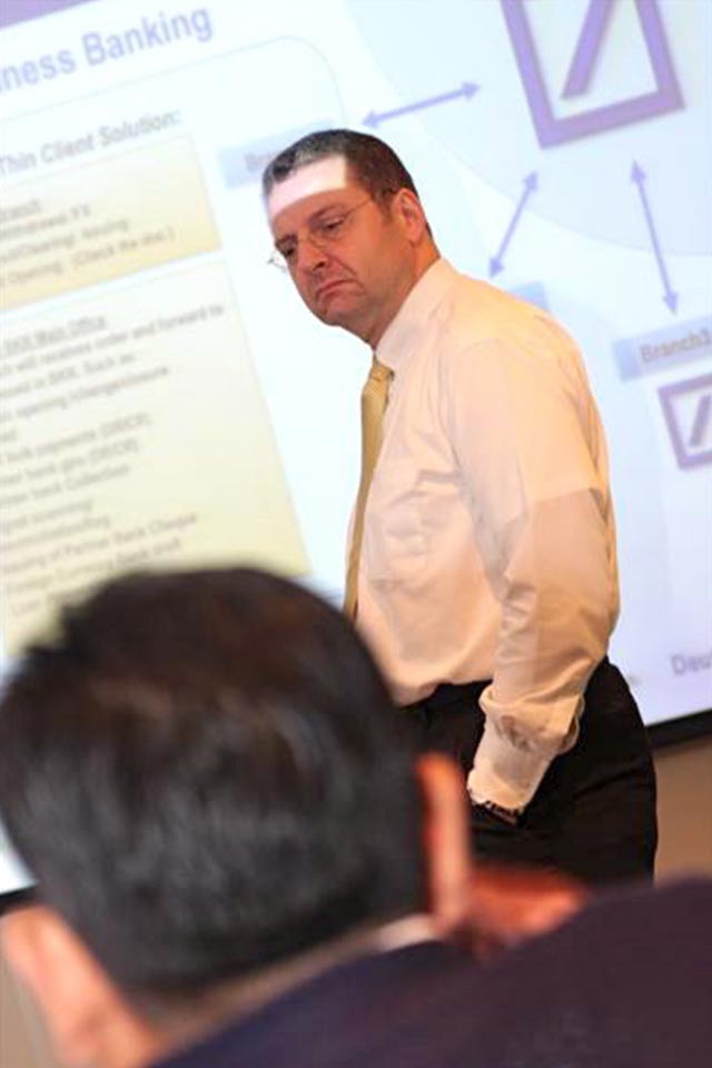 Deutsche Bank participant standing in front of a projected business banking slide