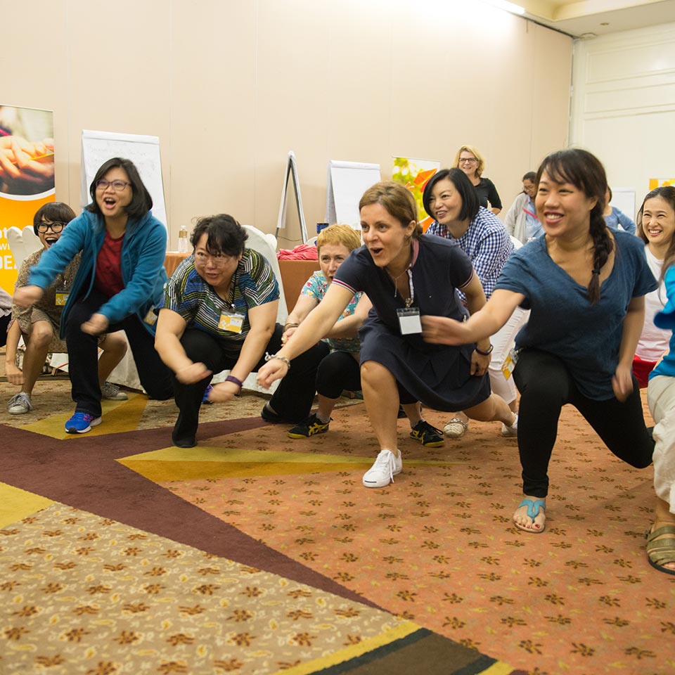 UNICEF staff doing an energizer exercise, crouching and reaching forward together