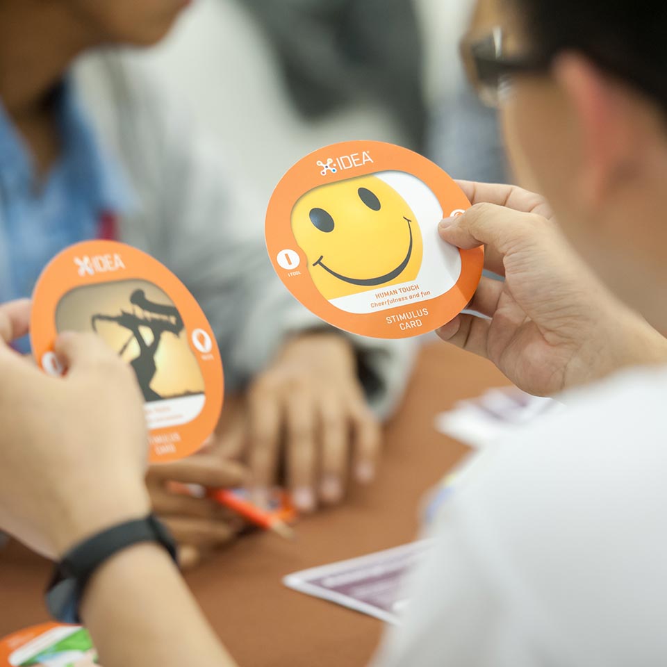 Participants holding orange X-IDEA stimulus cards in the UNICEF ideation session