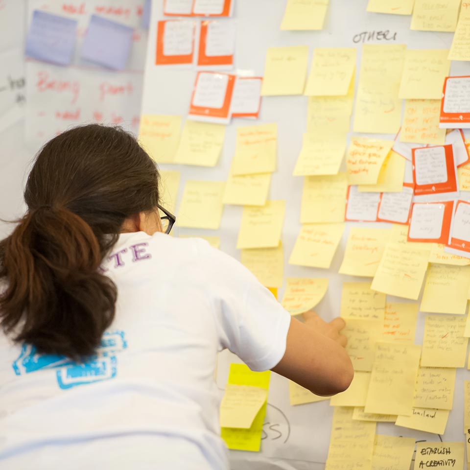 Participant adding a sticky note to a wall full of ideas at the UNICEF workshop