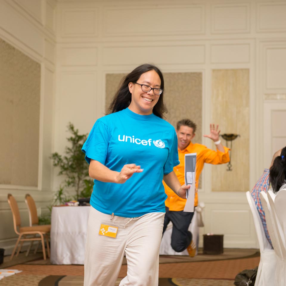 UNICEF staff member in a UNICEF T-shirt smiling during an energizer game