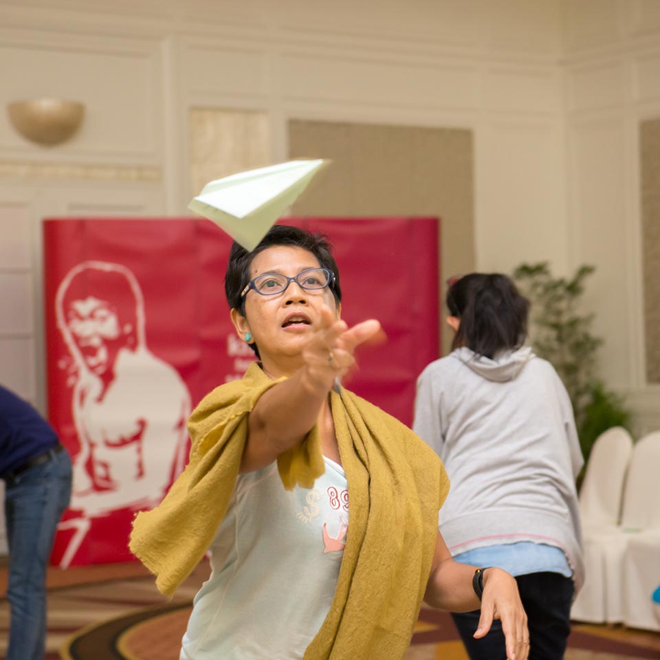 Participant launching a paper plane in front of a red banner at the UNICEF workshop