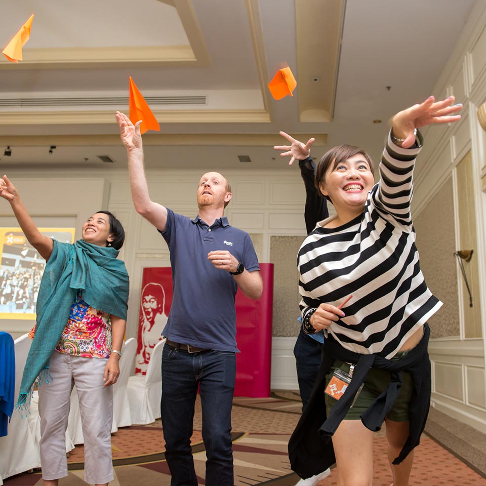 UNICEF participants throwing orange paper planes into the air