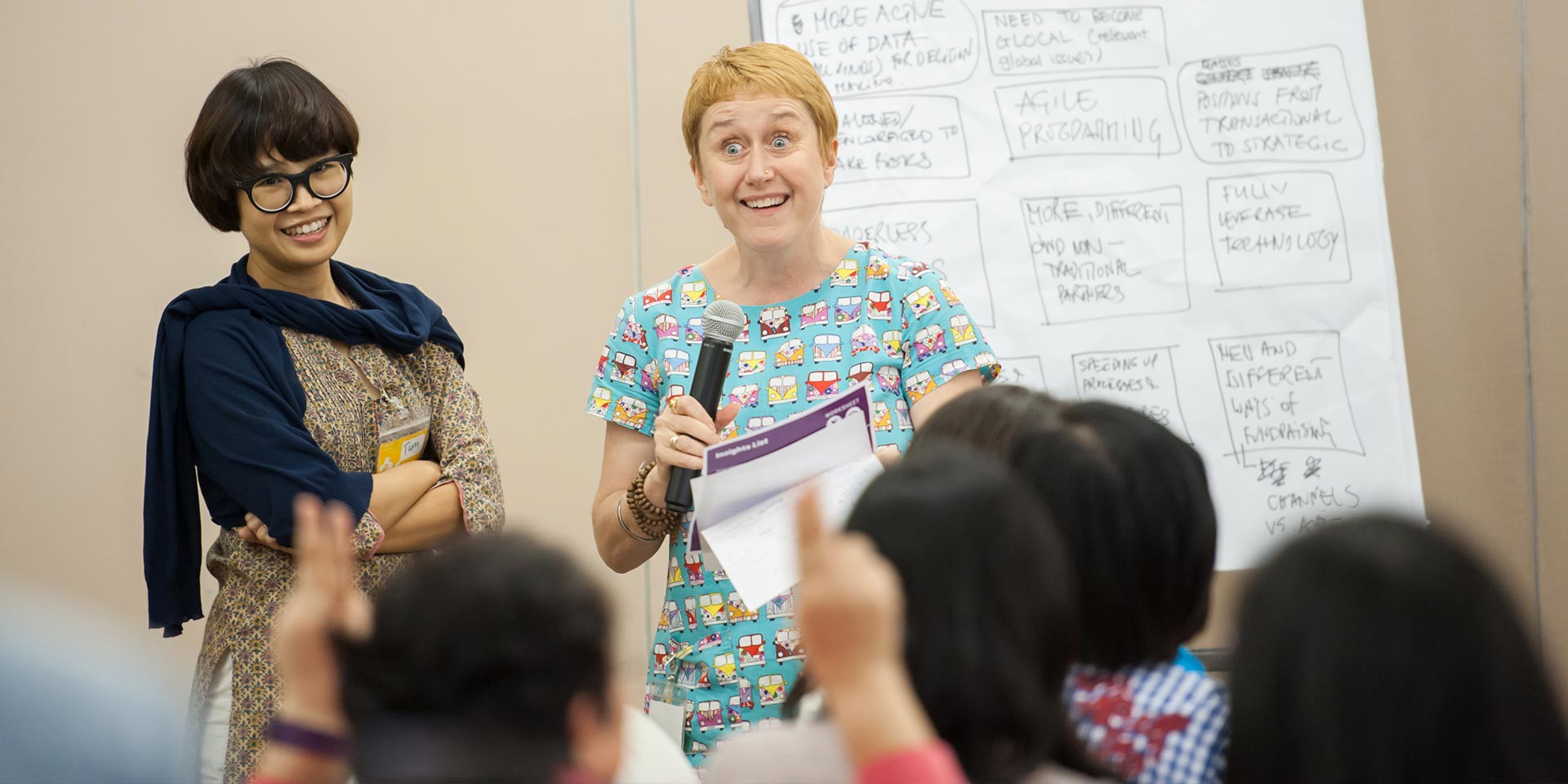 Two participants presenting their idea with a microphone in front of a flipchart, UNICEF