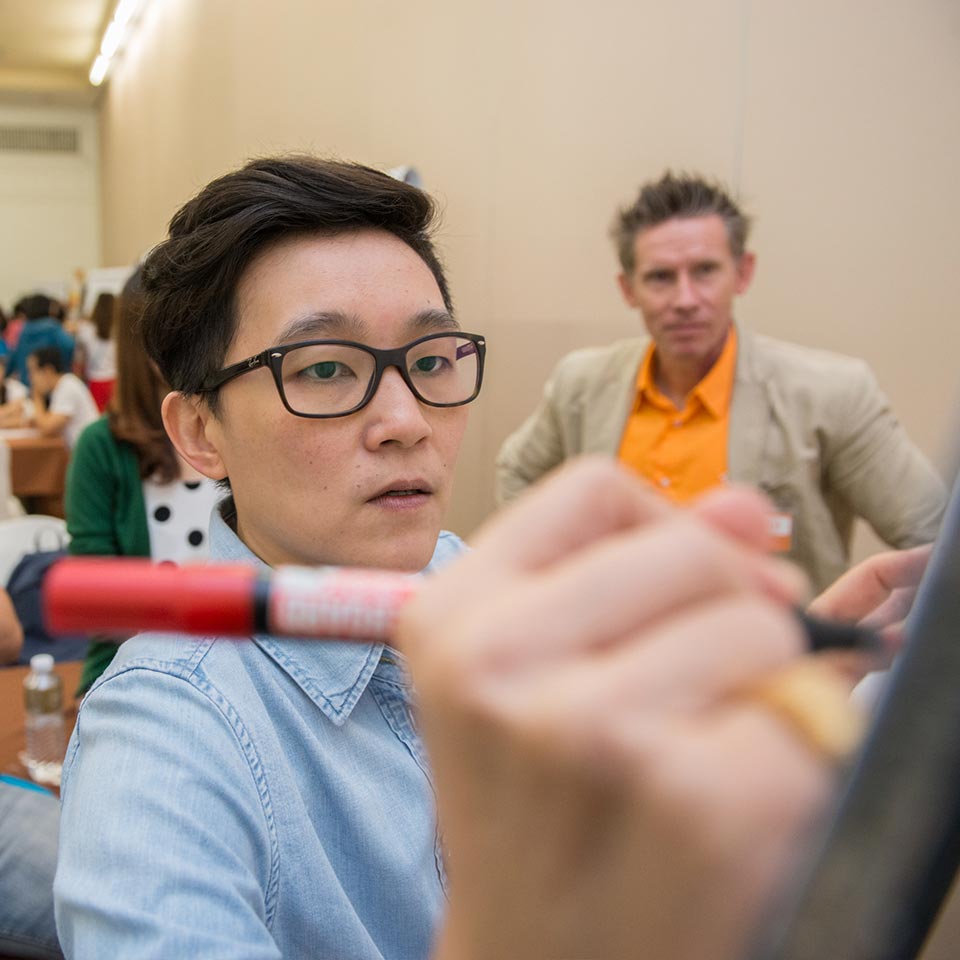 UNICEF participant writing with a red marker while the facilitator watches