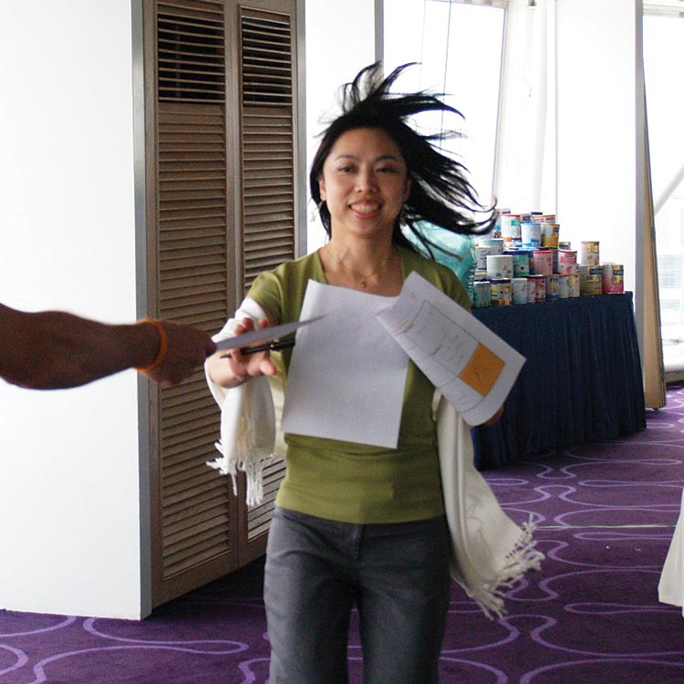 Smiling participant running to collect papers in a Mead Johnson workshop game
