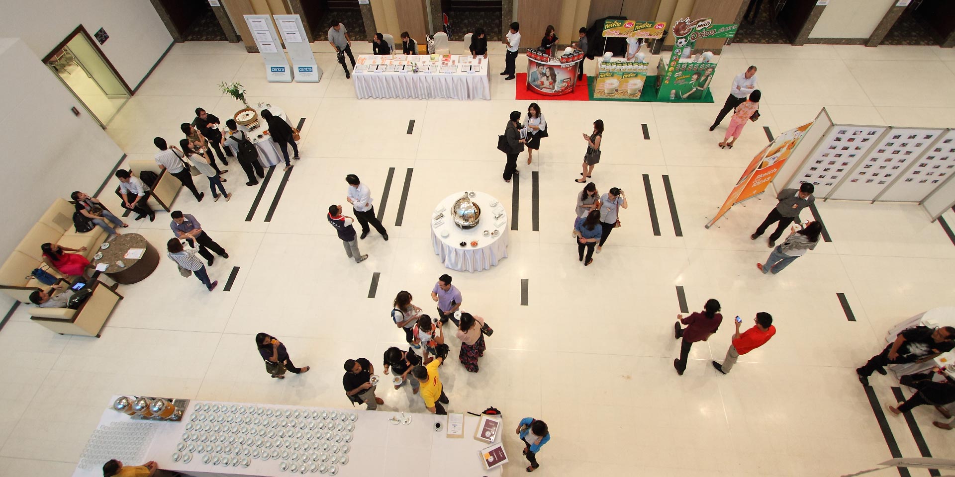 Overhead view of Nestle participants moving between stations in a large event hall