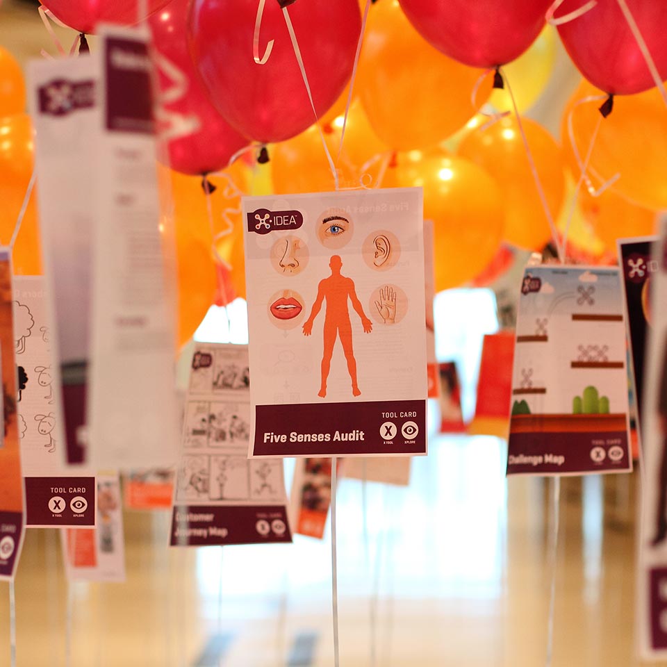 X-IDEA tool cards hanging under orange and red balloons at the Nestle event