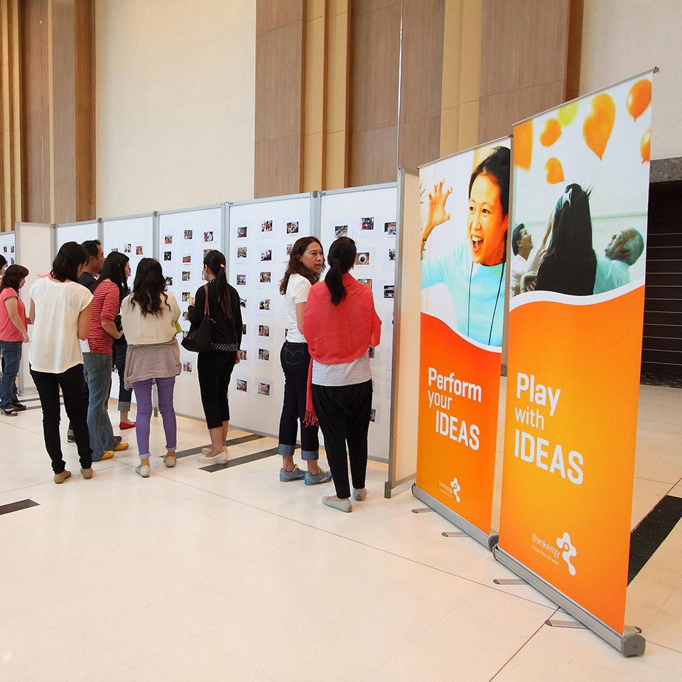 Nestle participants viewing a photo gallery wall beside Perform Your Ideas banners