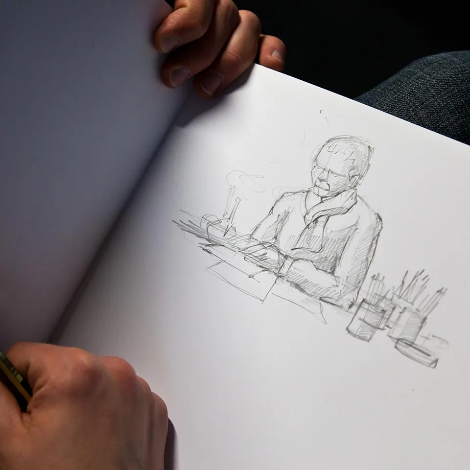 Pencil sketch of a person at a table in a sketchbook, BMW car interior project
