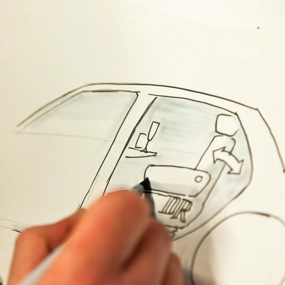 Hand sketching a car interior concept with a seat and cup holder, BMW project
