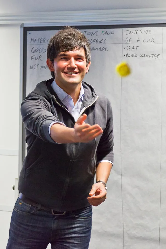 Smiling BMW participant tossing a ball in front of a flipchart of interior ideas