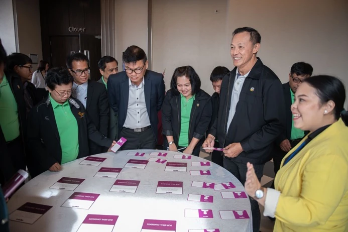 Workshop delegates standing around a table covered with TIPS profile cards