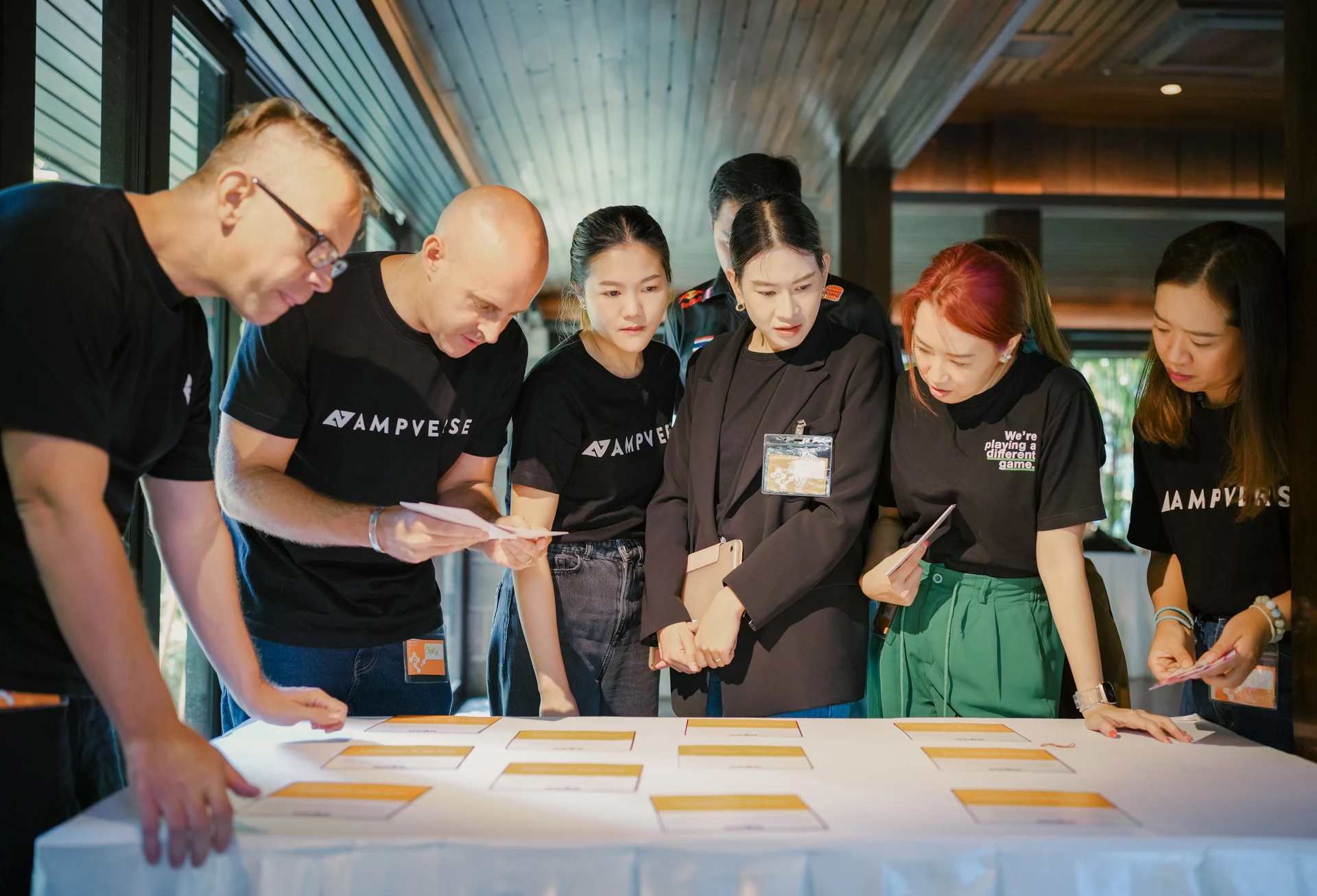 Ampverse team huddling over a table of cards during the TIPS workshop in Bangkok