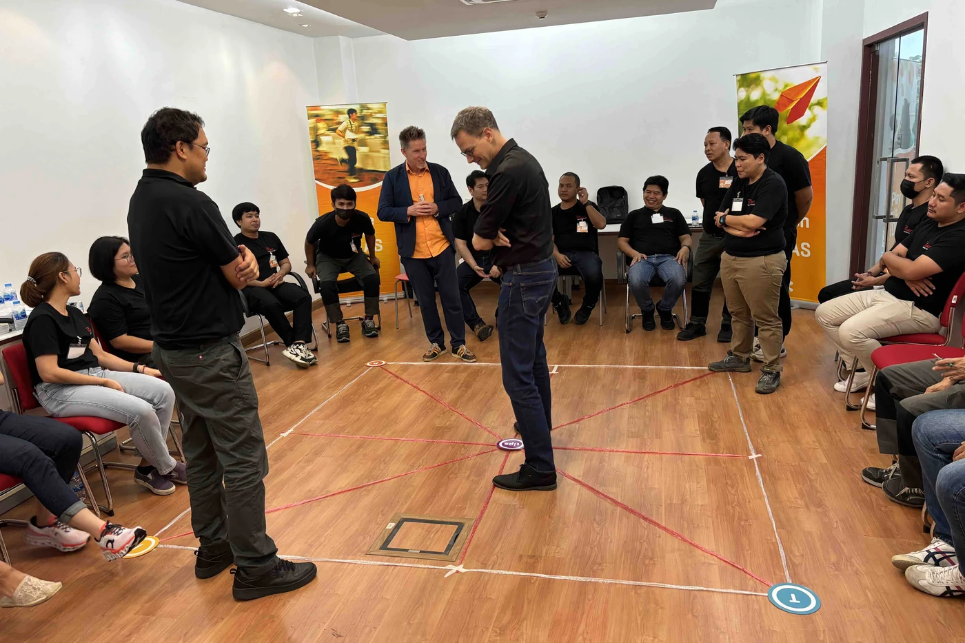 Dr. D and a participant on the TIPS Profiling Map on the floor, with the Ruwac Asia team around them