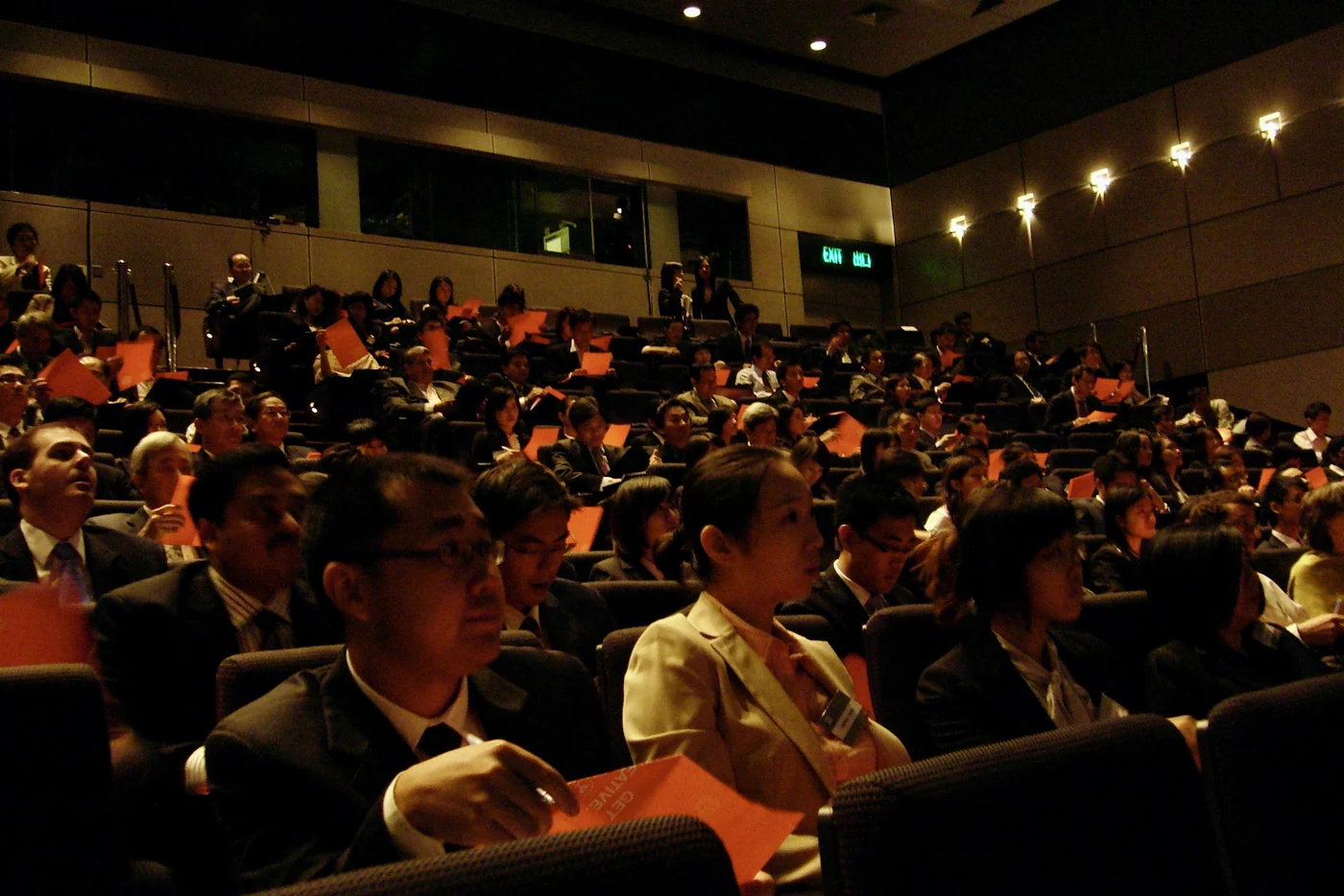 Conference audience holding orange paper planes during the Idea Plane exercise