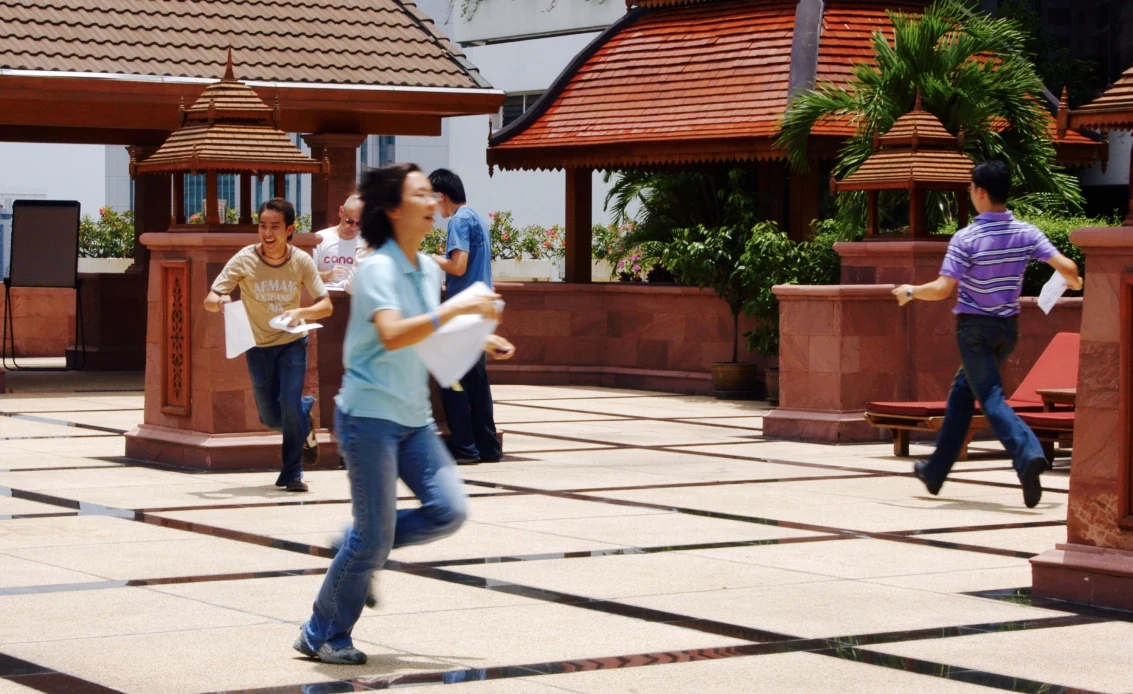 Merck Thailand workshop participants running across a courtyard during an ideation exercise