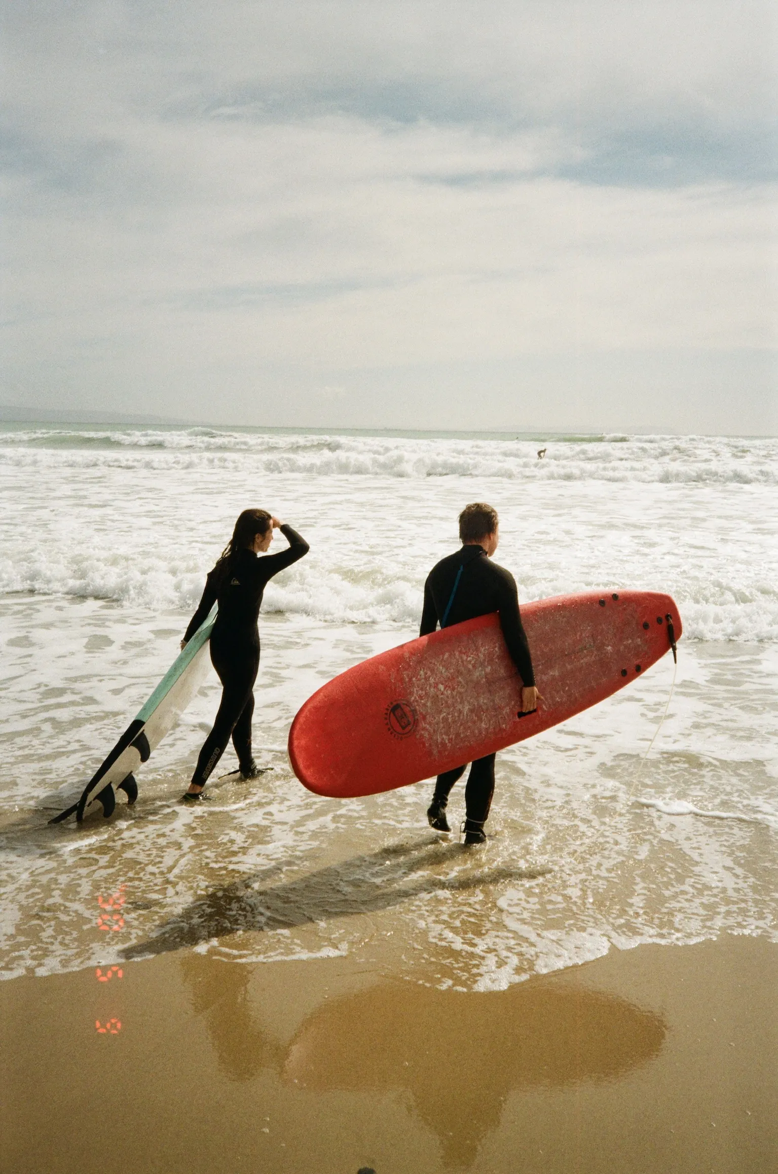 Surfers walking with boards on a cloudy beach