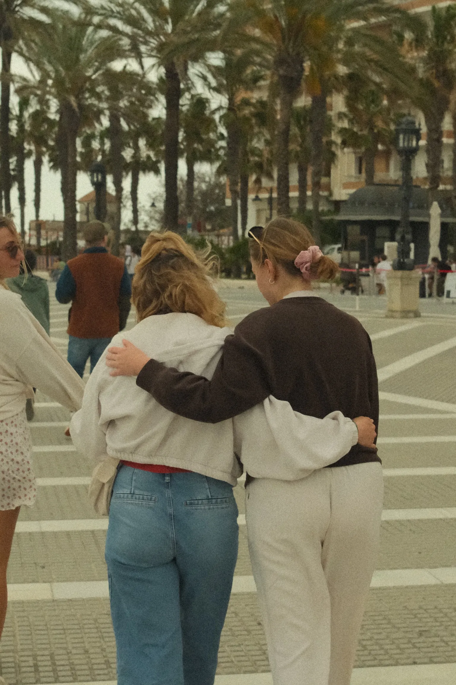 Hug between two women at an outdoor event near palm trees