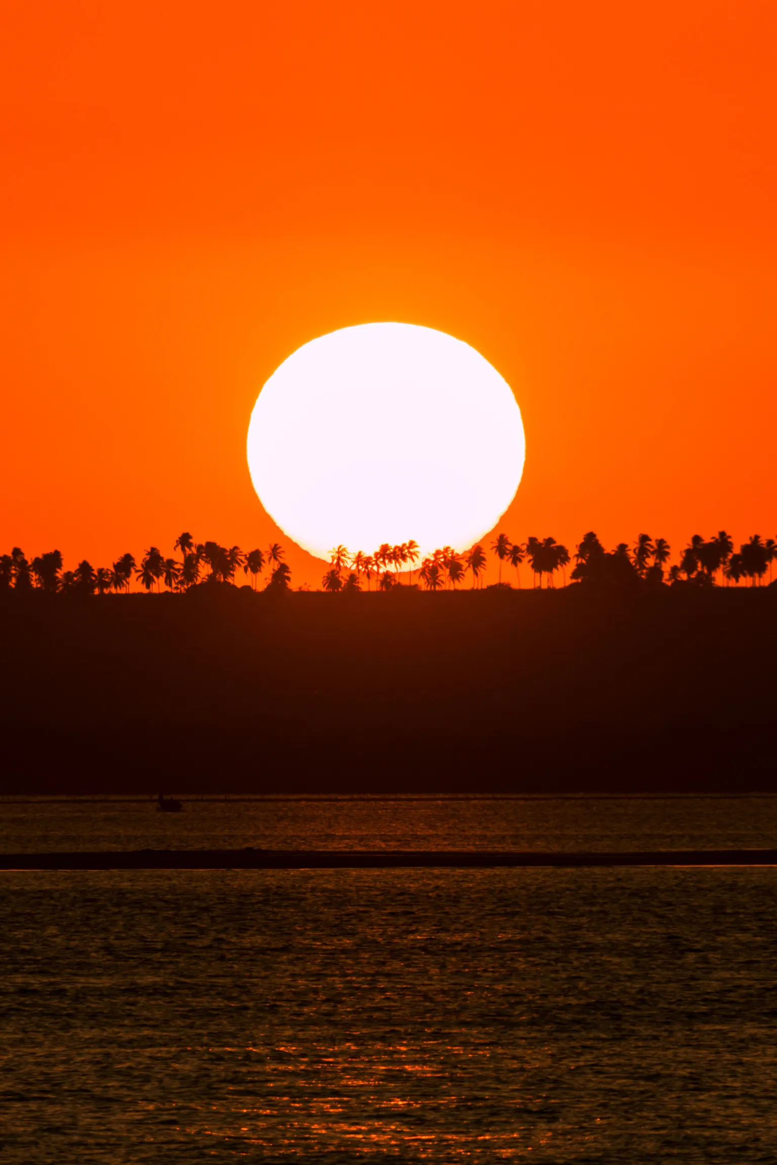 Sunset over the ocean, orange sky and silhouette of waves