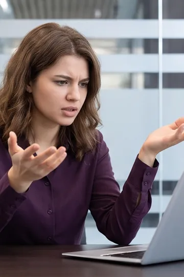 Woman at laptop looking confused