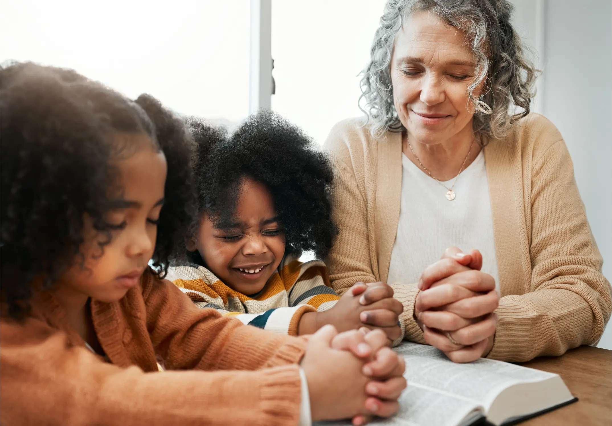 senior woman praying with kids