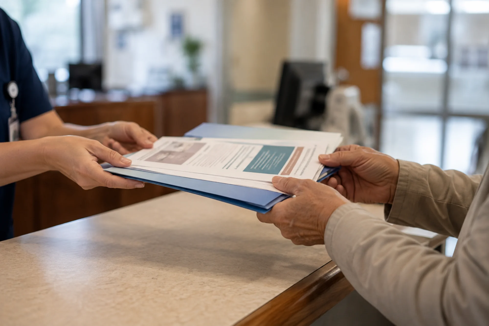 Clinician handing a patient an information folder at a clinic front desk.