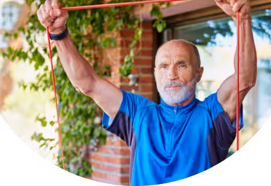Elderly man holding a resistance band over his head at home