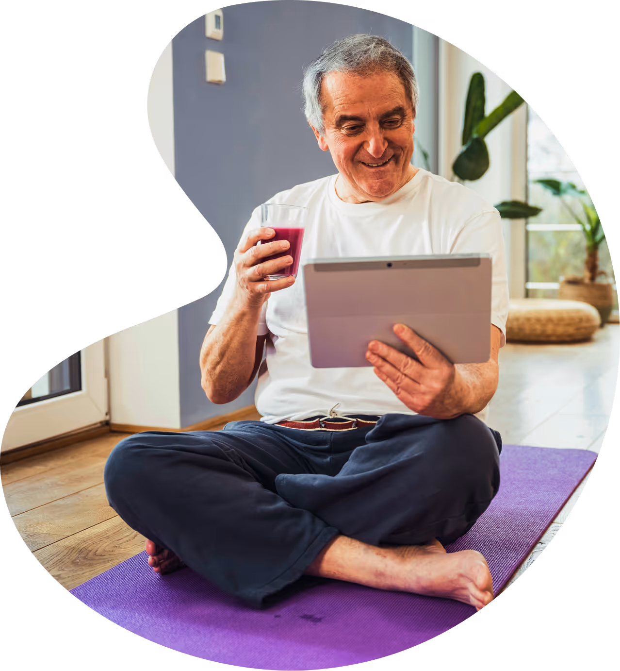 Elderly man smiling while holding a tablet computer at home