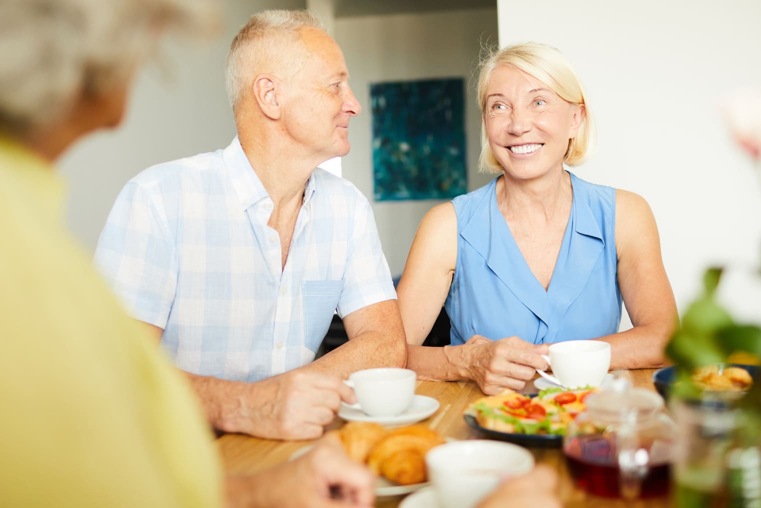Smiling mature couple with dentures from Saberton having coffee and breakfast with friends