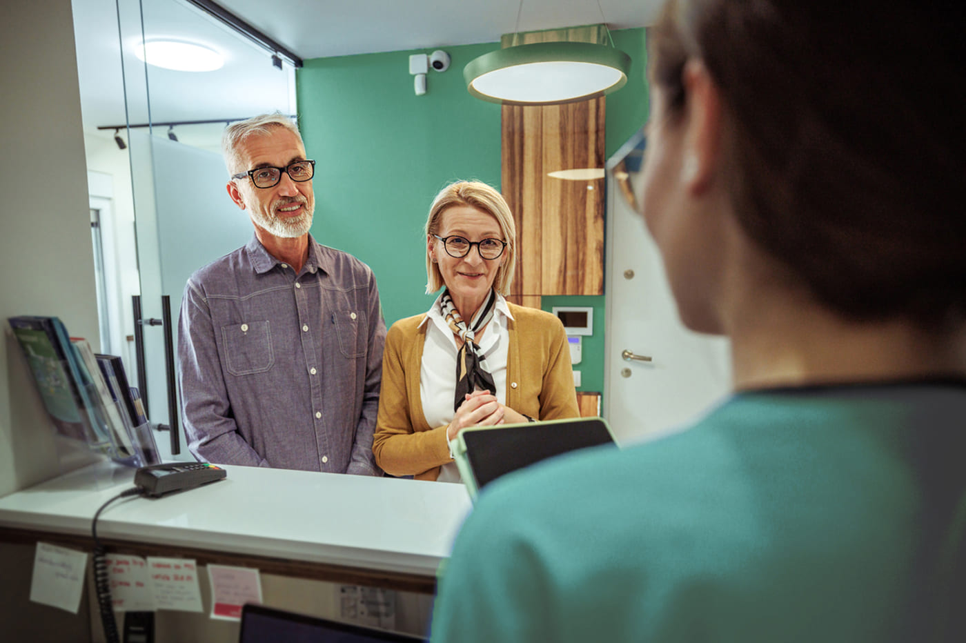 Older couple speaking with a dental receptionist about denture insurance and Canadian Dental Care Plan (CDCP) coverage options