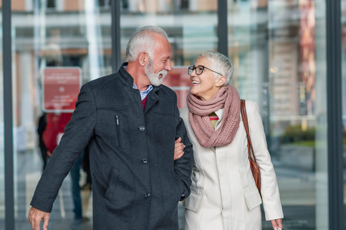 Smiling senior couple walking together after a dental appointment, showing confidence with new dentures