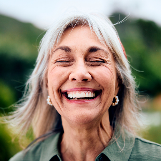happy woman with dentures smiling and doing outdoor yoga