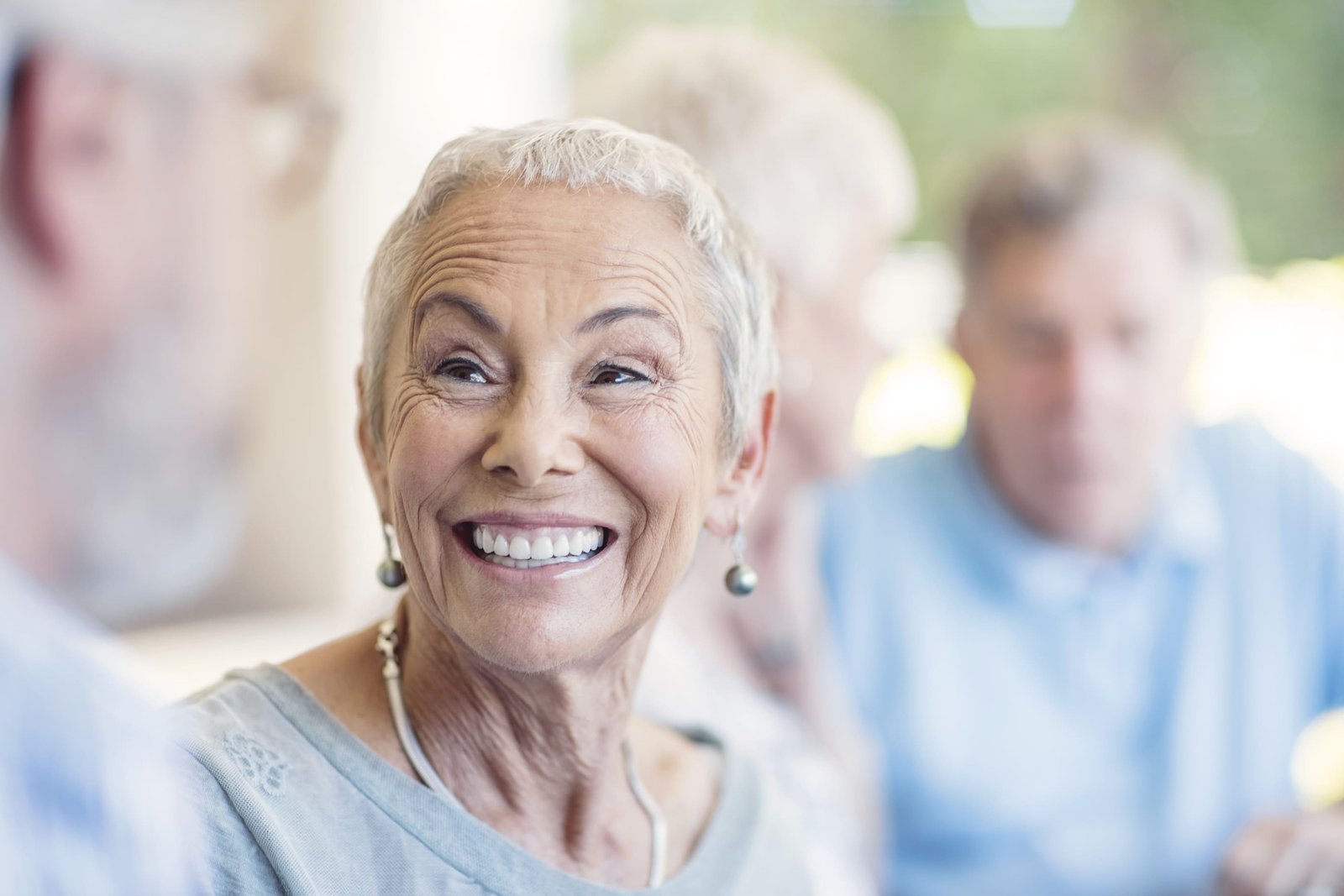 Confident senior female patient with a bright smile discussing dental care with her attentive female dentist in a warm, inviting clinic setting, reflecting positive patient experiences with Saberton dental services.
