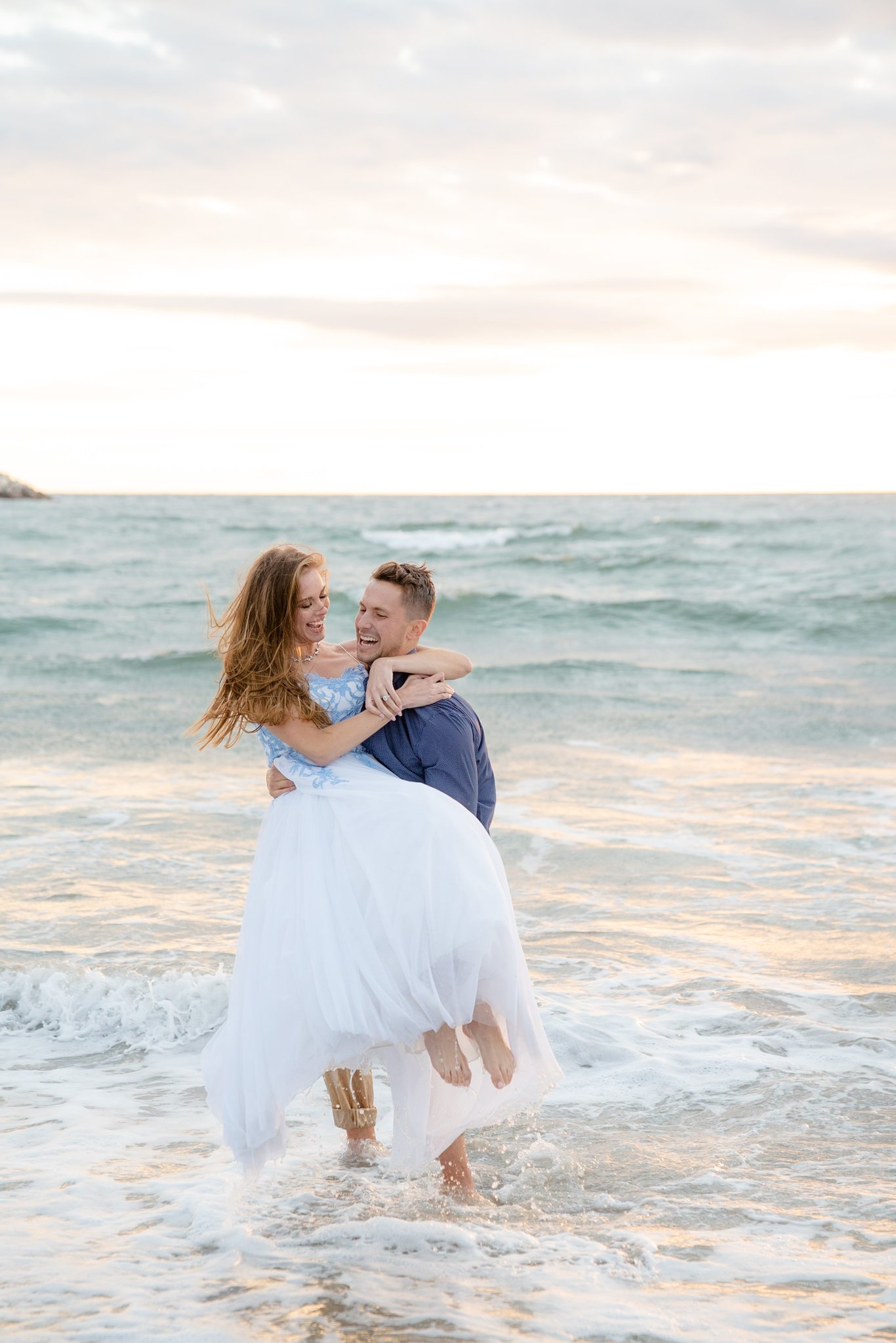 Venice Beach engagement session couple laughing groom picks up his bride in the water.