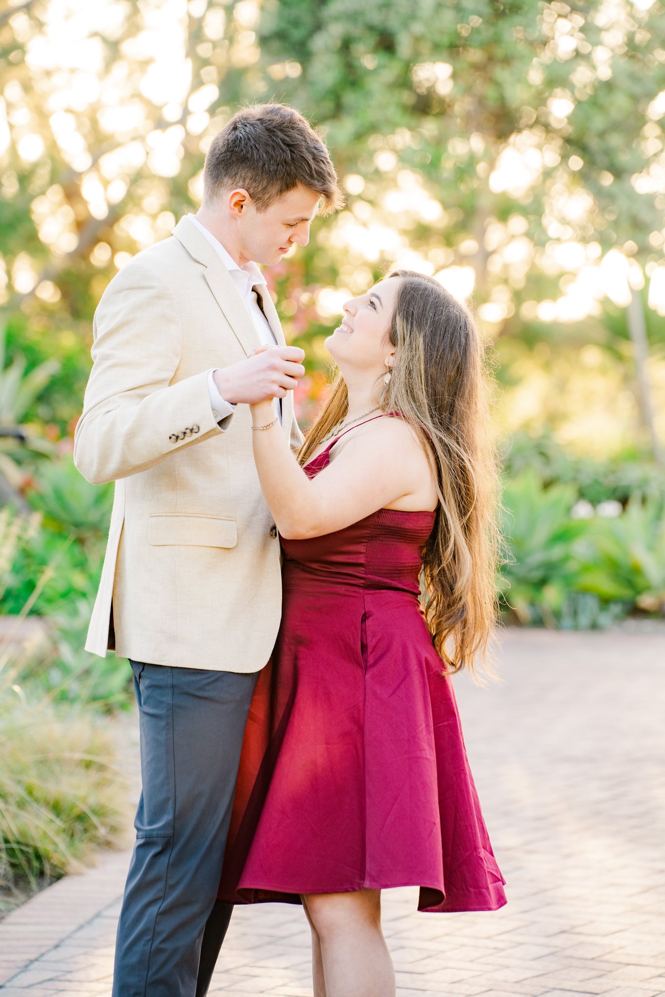 engagement photos couple in burgundy dress in flower garden dancing