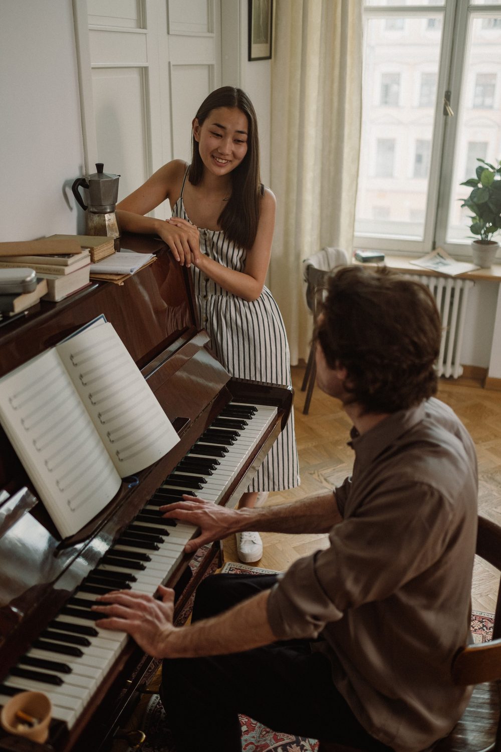 Two people at a piano in a city apartment