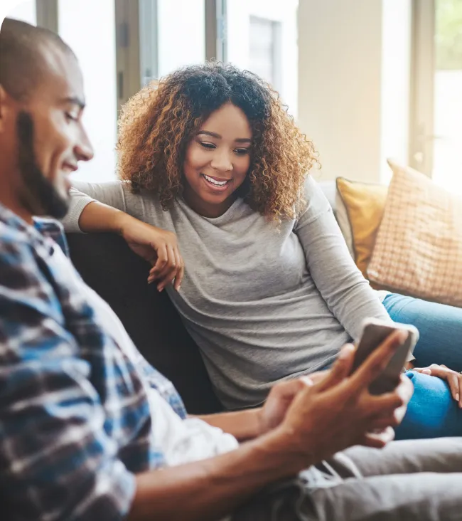 Pareja relajada en casa consultando el móvil