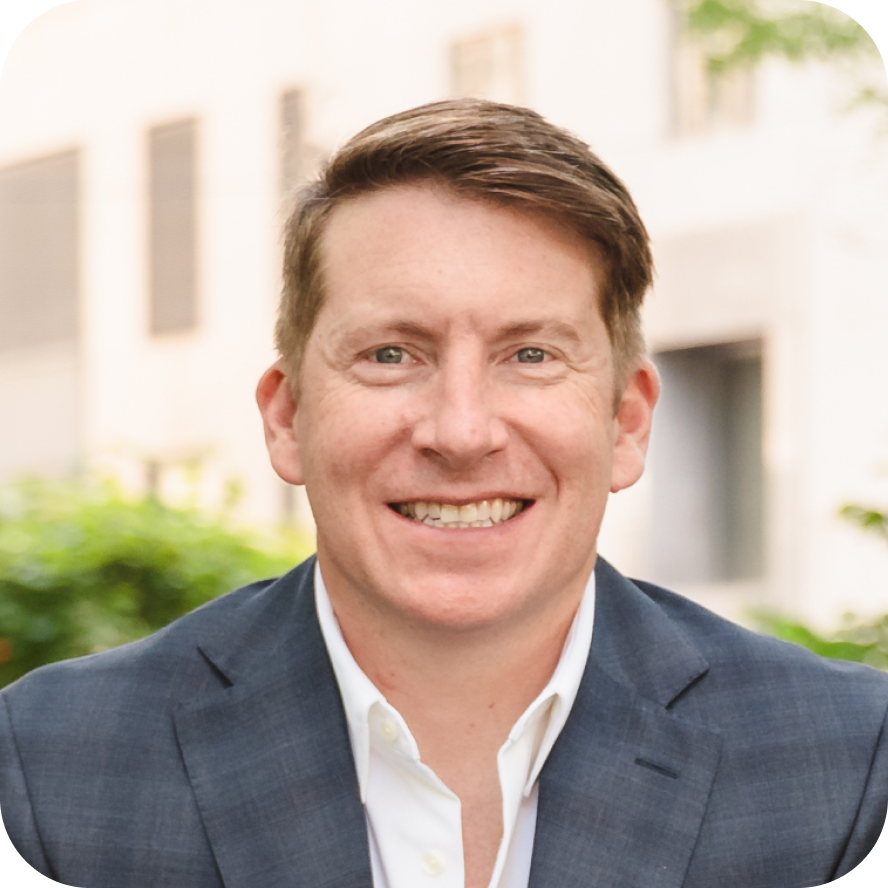 Man with brown hair in a suit sitting outside