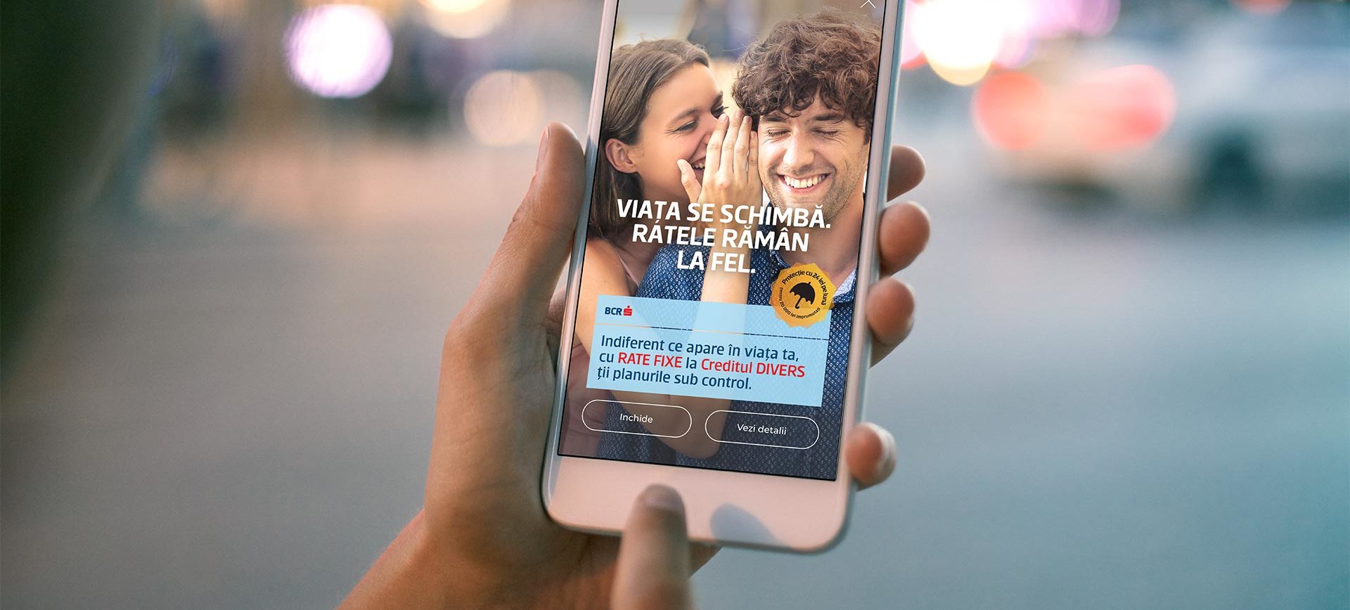 Mano sosteniendo un celular con un anuncio de dos personas sonrientes