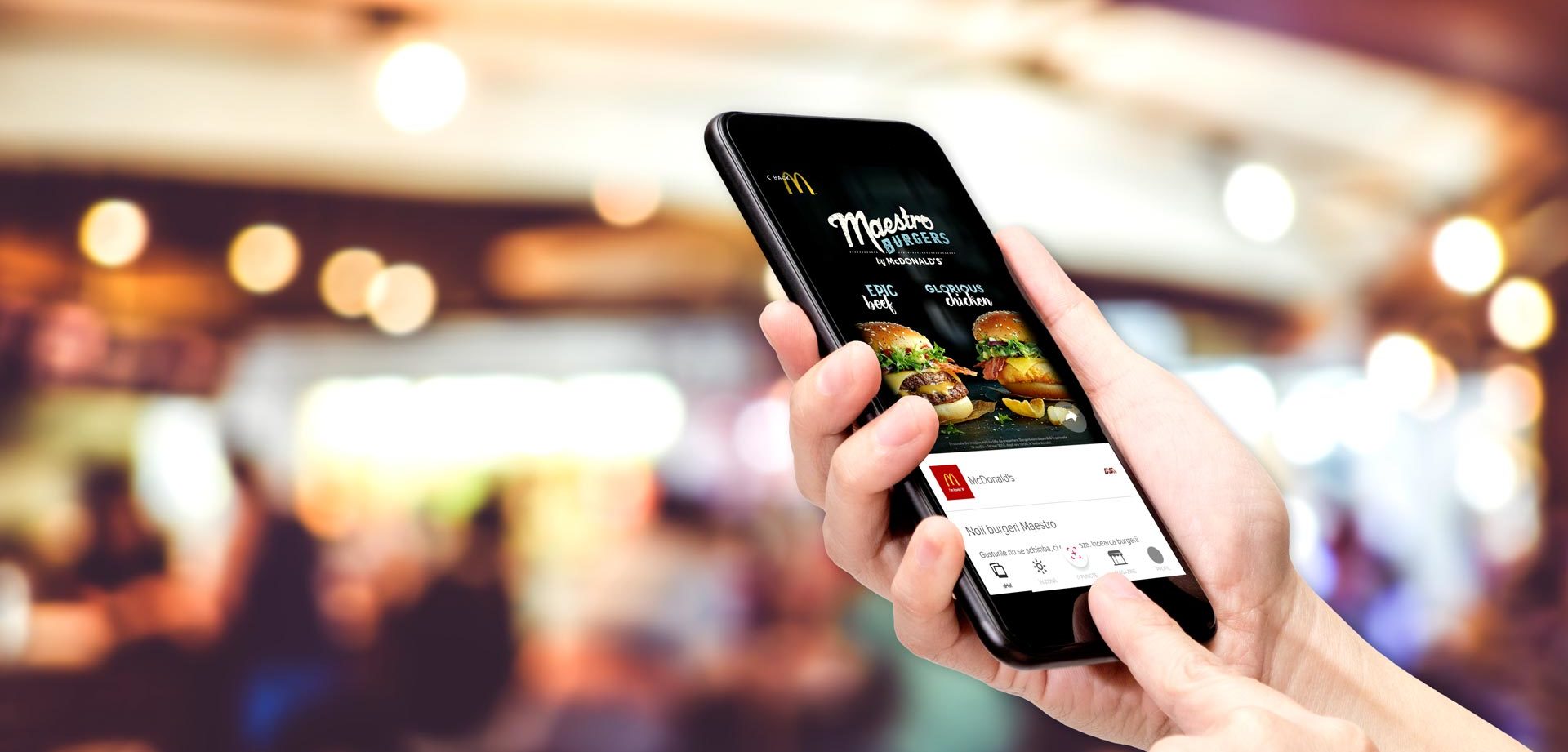 Mano sosteniendo un celular con una app de comida dentro de un centro comercial