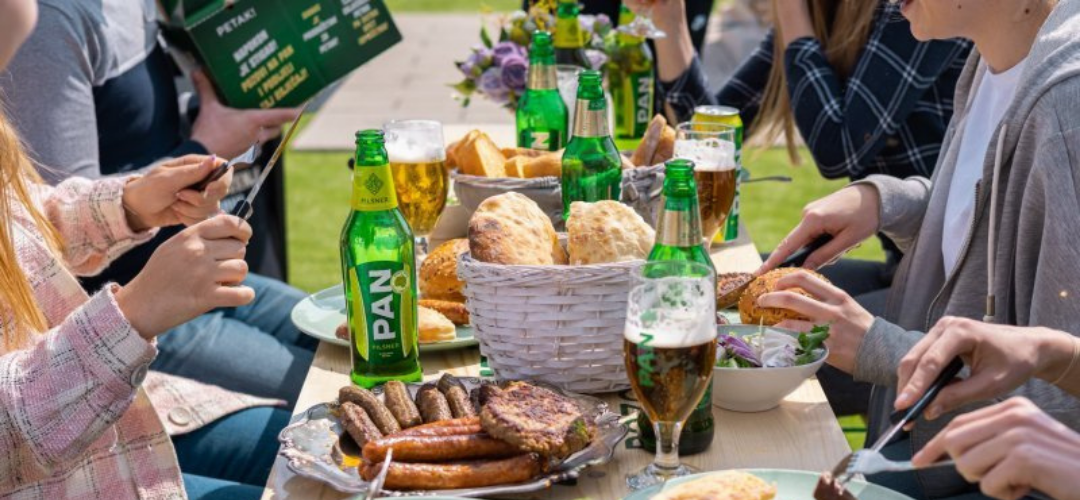 Personas compartiendo comida en una mesa con botellas de cerveza Pan