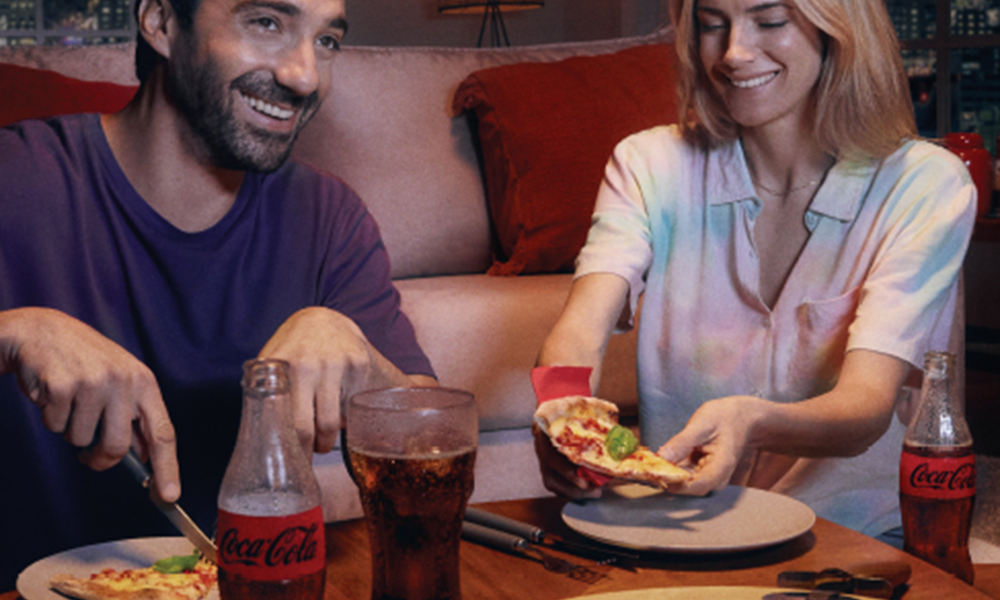 Amigos compartiendo comida y Coca-Cola en una mesa