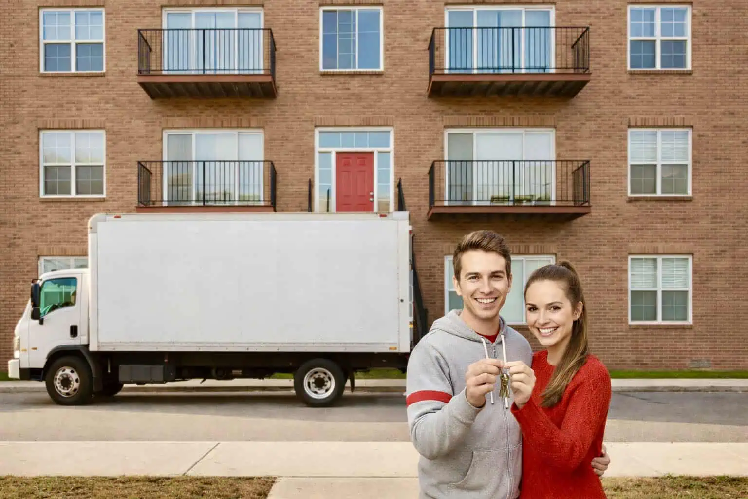 Mladý pár s klíči před domem a stěhovacím autem bez nápisu - generováno AI 